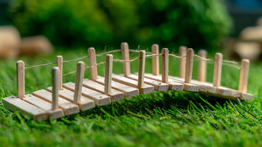 miniature popsicle stick bridge placed on green gr